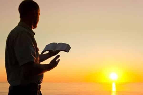 homem lendo a bíblia no por do sol
